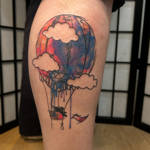 A watercolor air balloon piece on the calf, featuring vibrant and dreamy colors. This design captures the whimsical essence of a hot air balloon floating through the sky, creating a beautiful and artistic piece that stands out! 